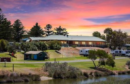 A photo looking over the river towards the meals room with a beautiful pink and blue sunset in the background