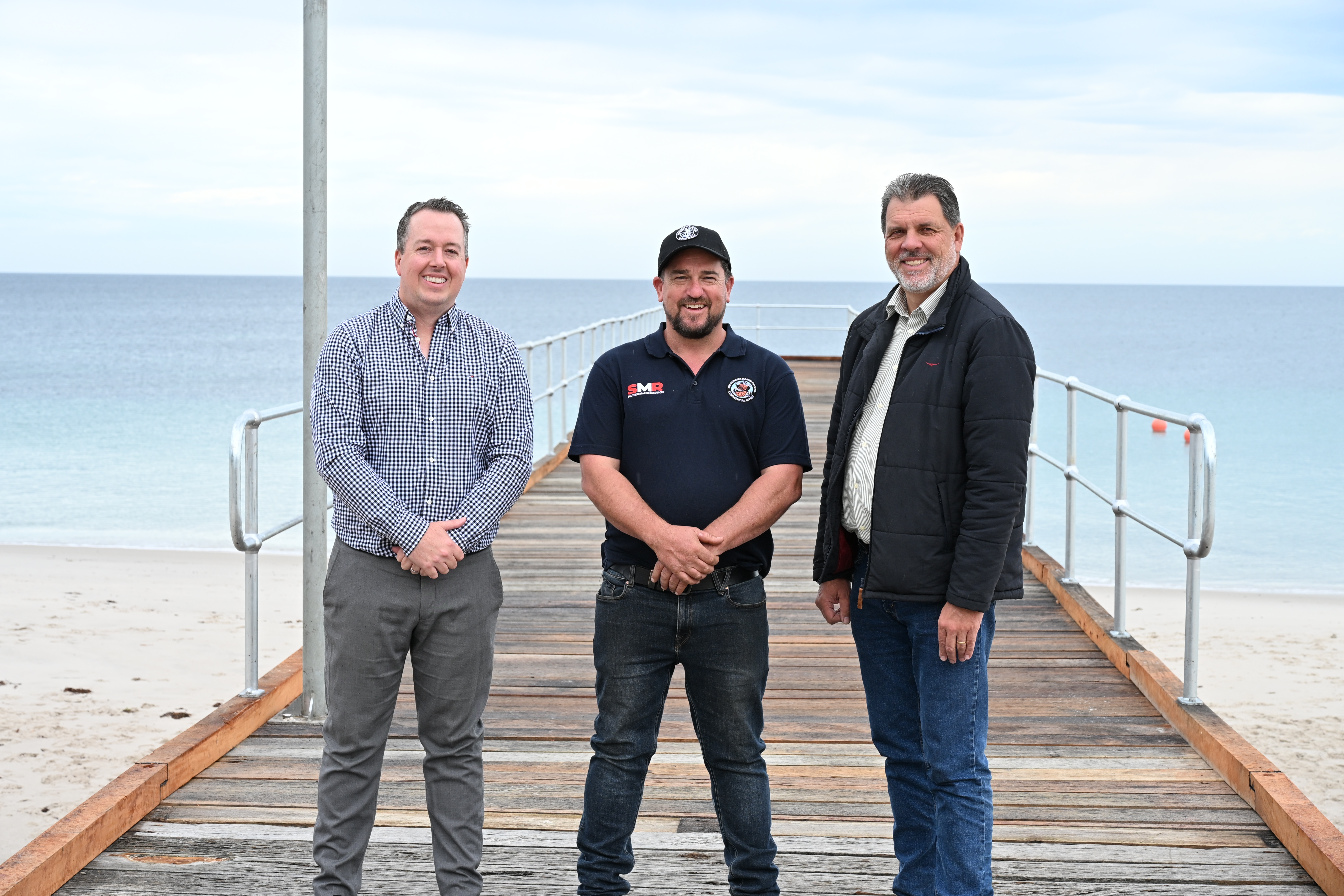 CEO Nathan Cunningham, Shaun Willamson (Southern Marine Resources Operations Manager) and Mayor Darryl Houston standing on a jetty and smiling.