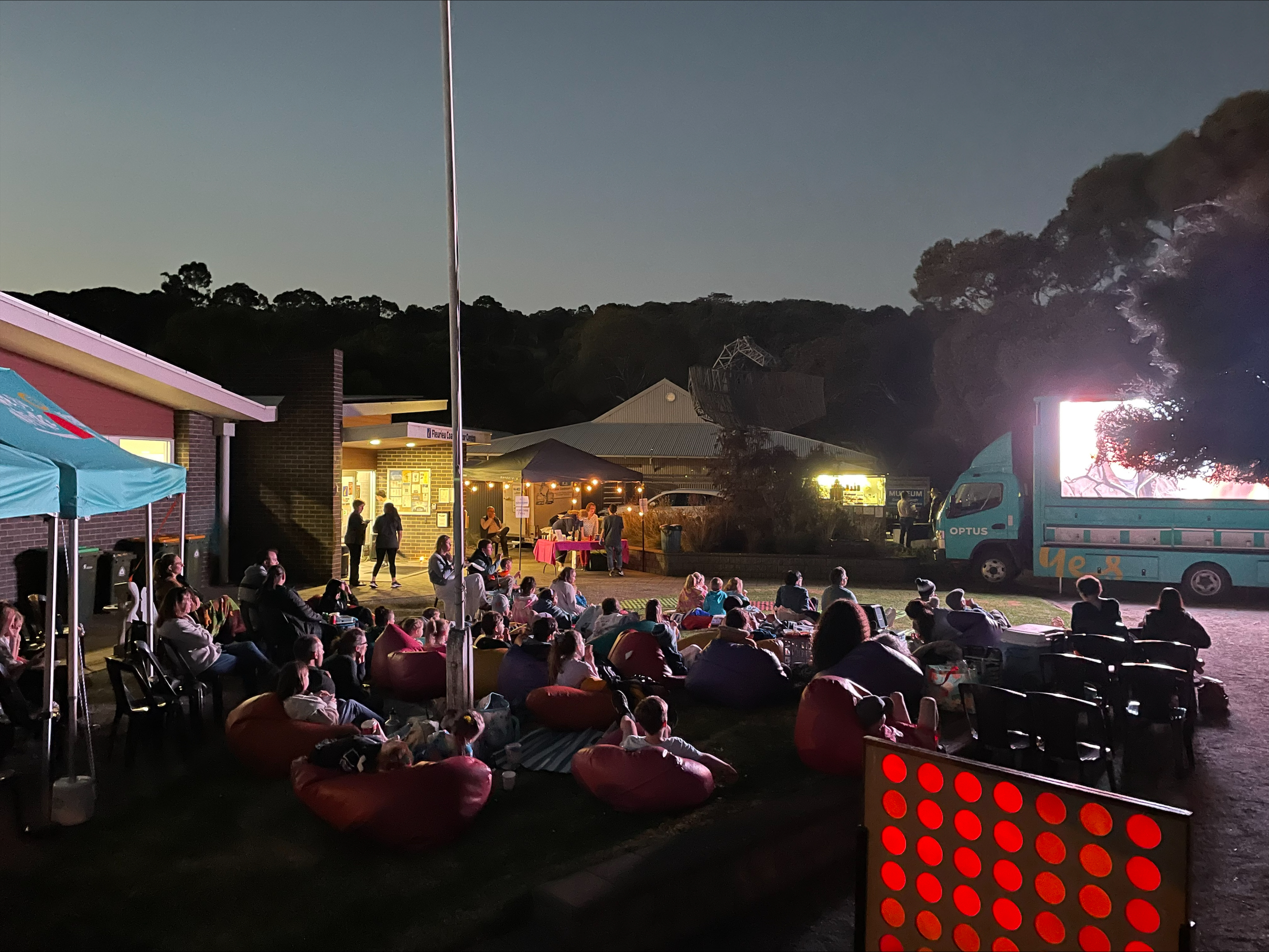 A photo of people sitting in beanbags watching a movie on a movie truck