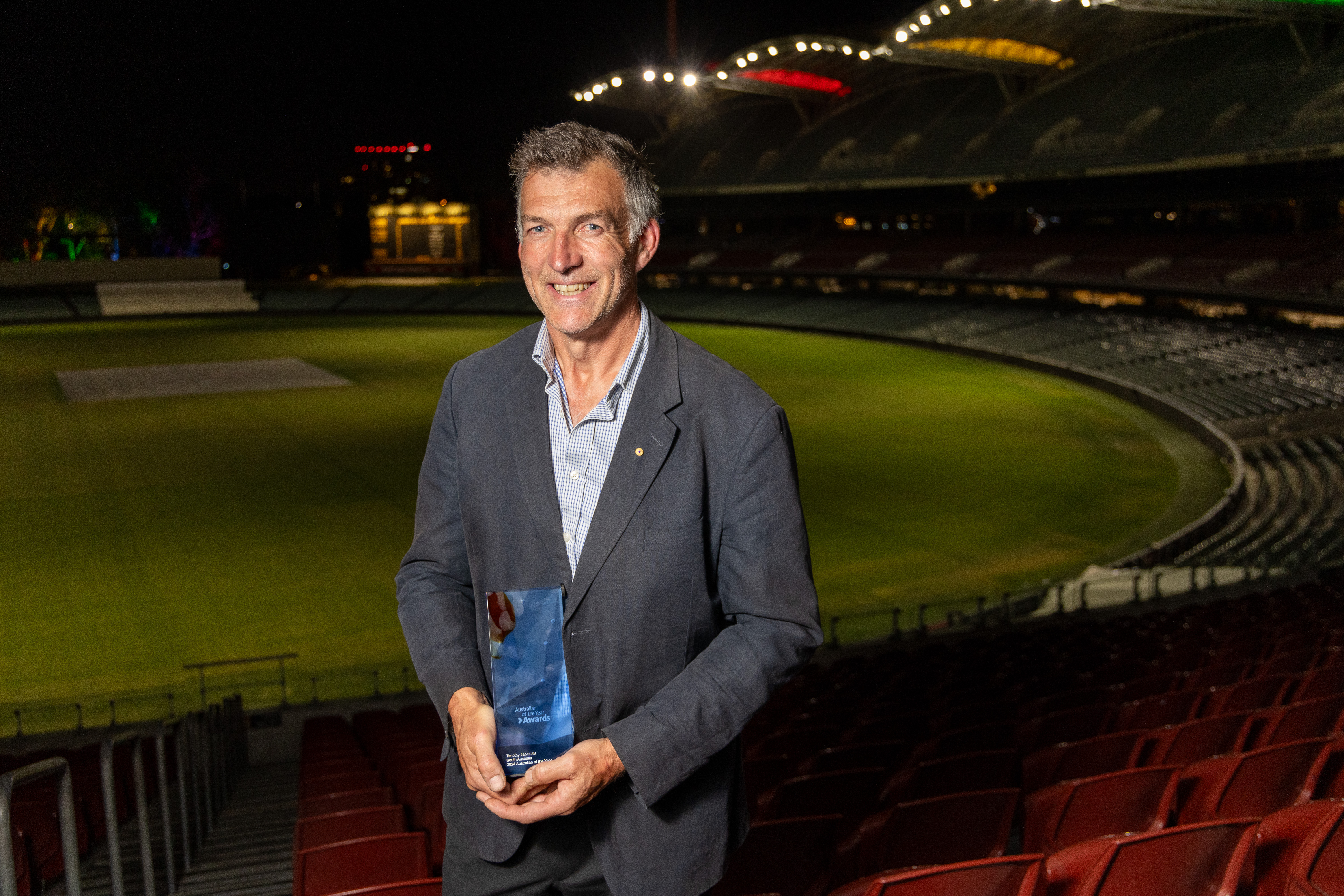 A photo of a man holding a trophy and smiling